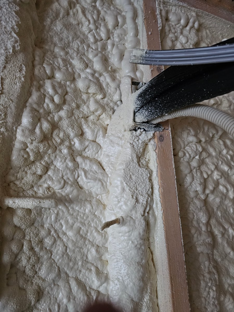 Mini-split lines sealed into closed-cell spray foam where they run down a stud wall
