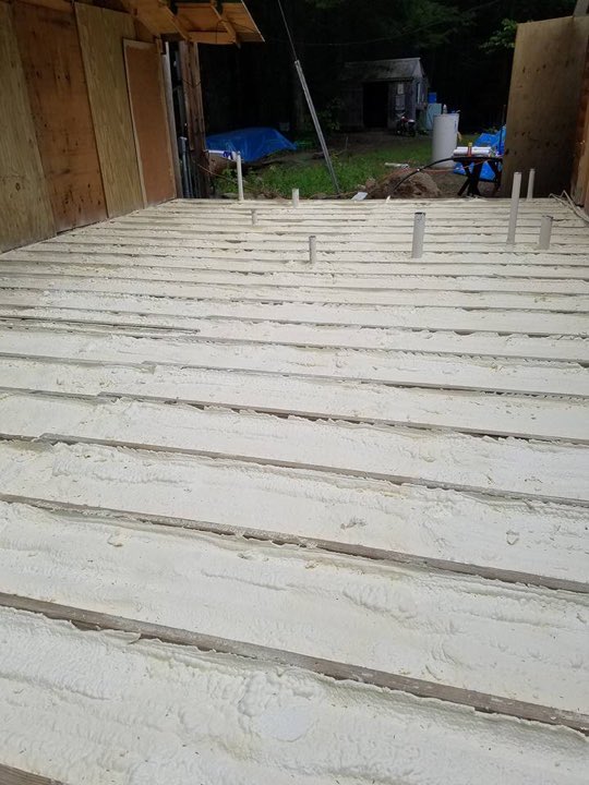 Underside of a floor deck insulated with spray foam between the joists