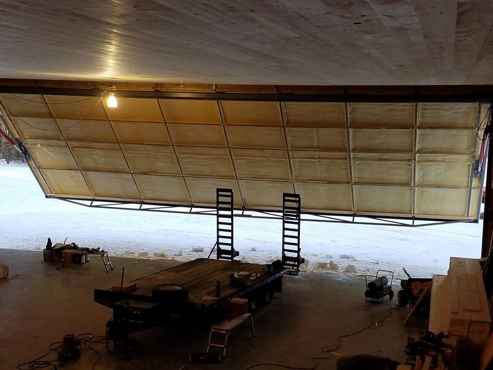 Overhead aircraft hangar door insulated with spray foam, with snow visible outside