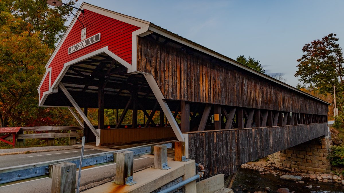 The Honeymoon covered bridge over the Ellis River in Jackson, New Hampshire, its red portal signed JACKSON, N.H.